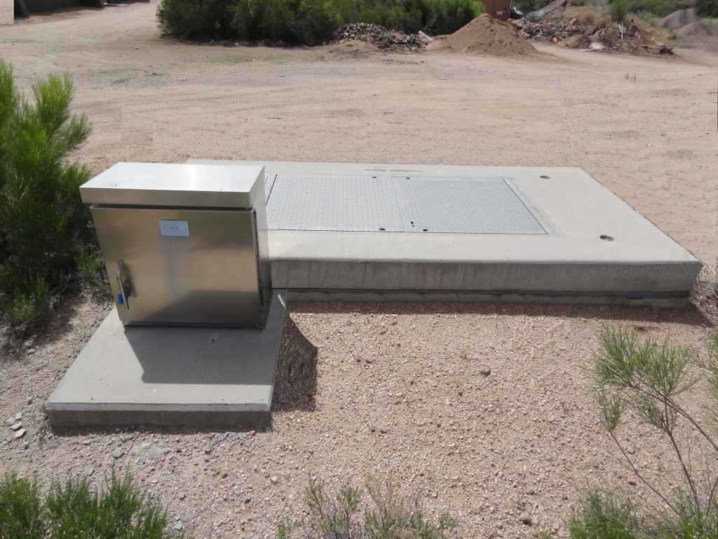 A metal box is placed in the middle of a dirt field by MGC contractors.