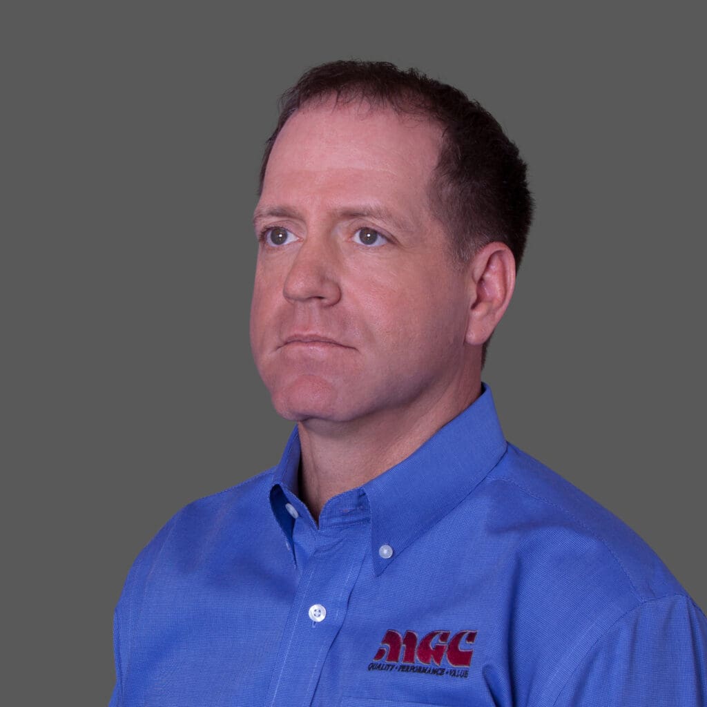 A man in a blue shirt is standing in front of a gray background, about mgc contractors.