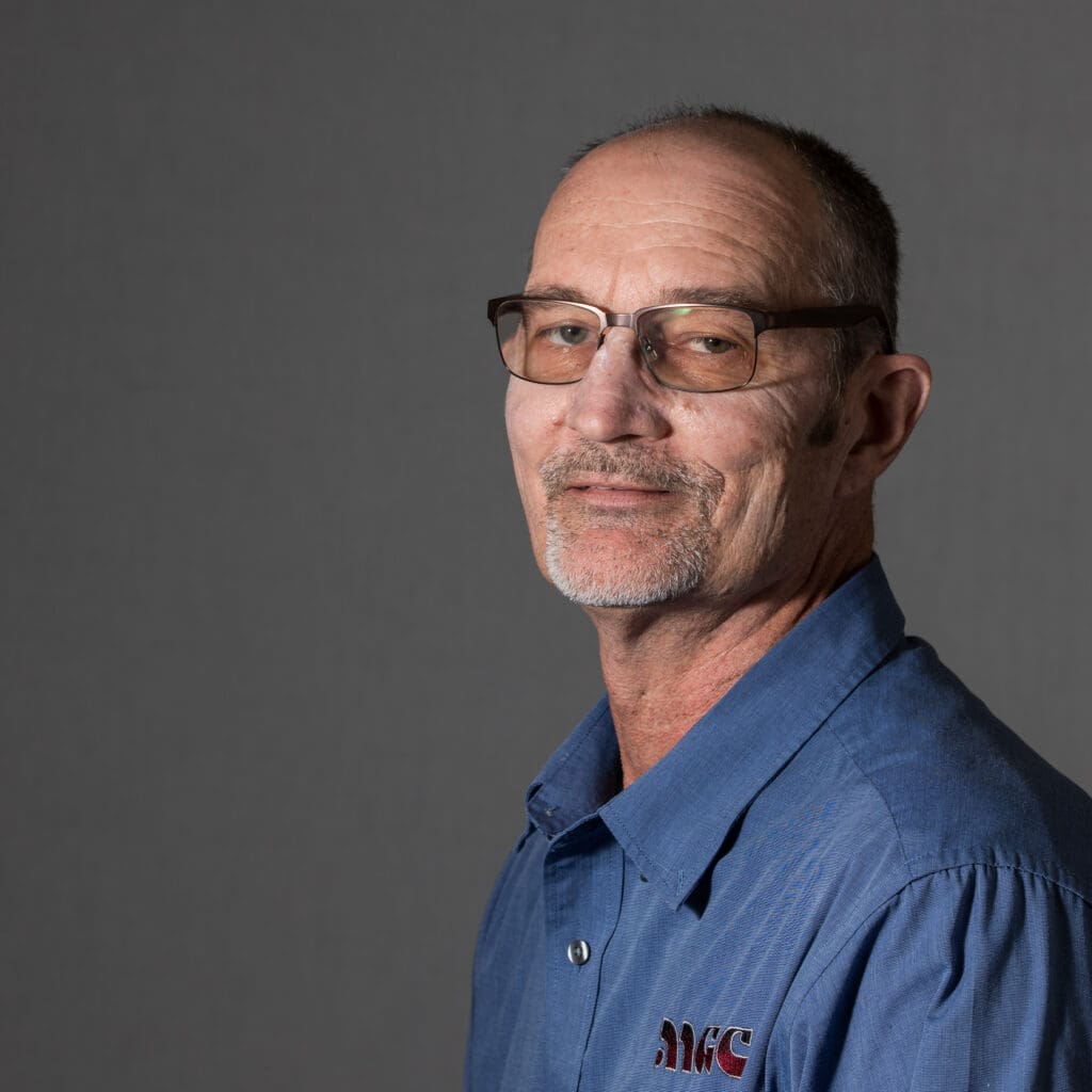 A man wearing glasses and a blue shirt affiliated with MGC Contractors.