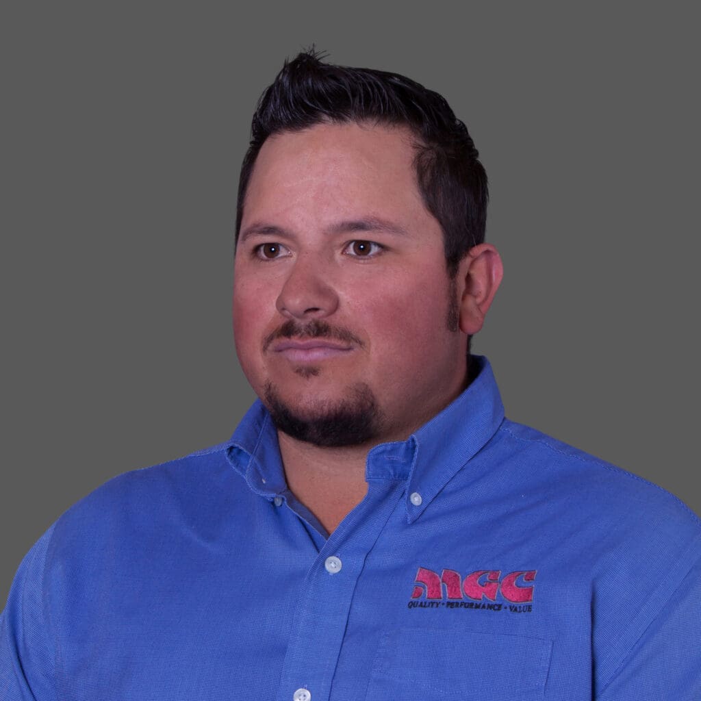 A man in a blue shirt standing in front of a gray background who works for mgc contractors.