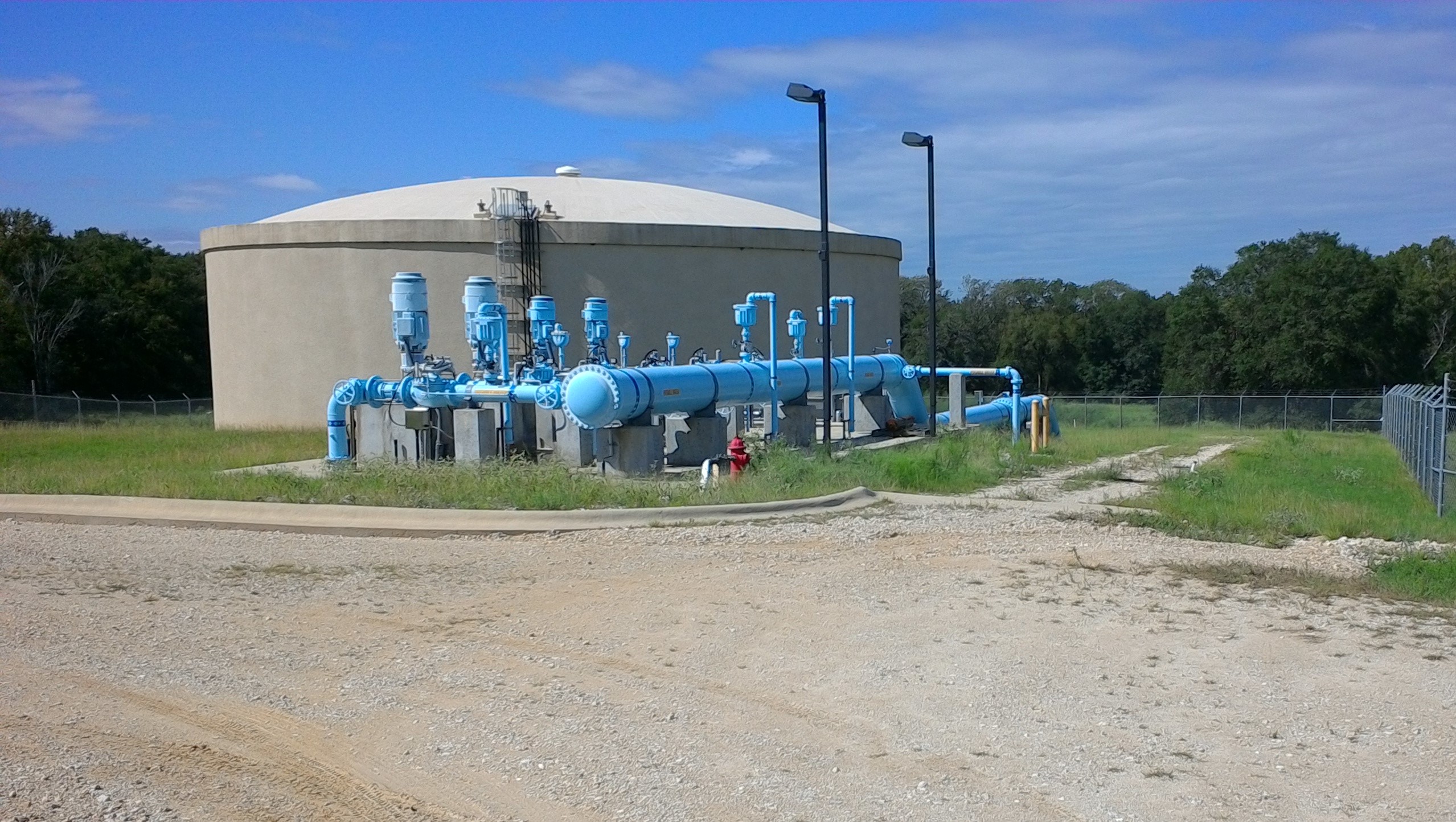A water storage tank with blue pipes in front of it.