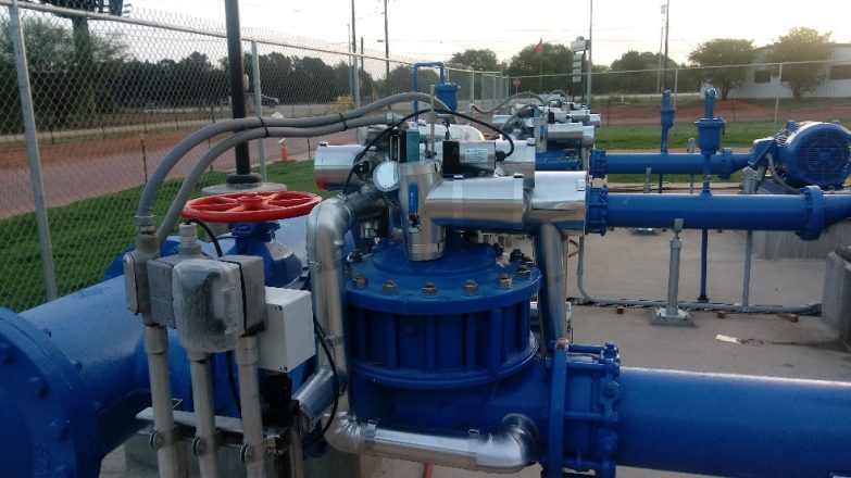 A group of blue pipes and valves in a field.